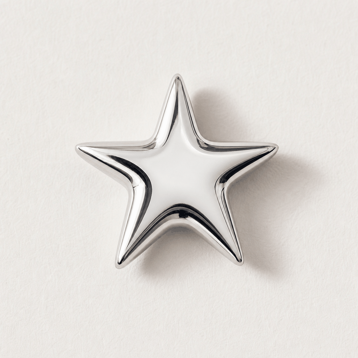 A real polished chrome star charm on white paper
